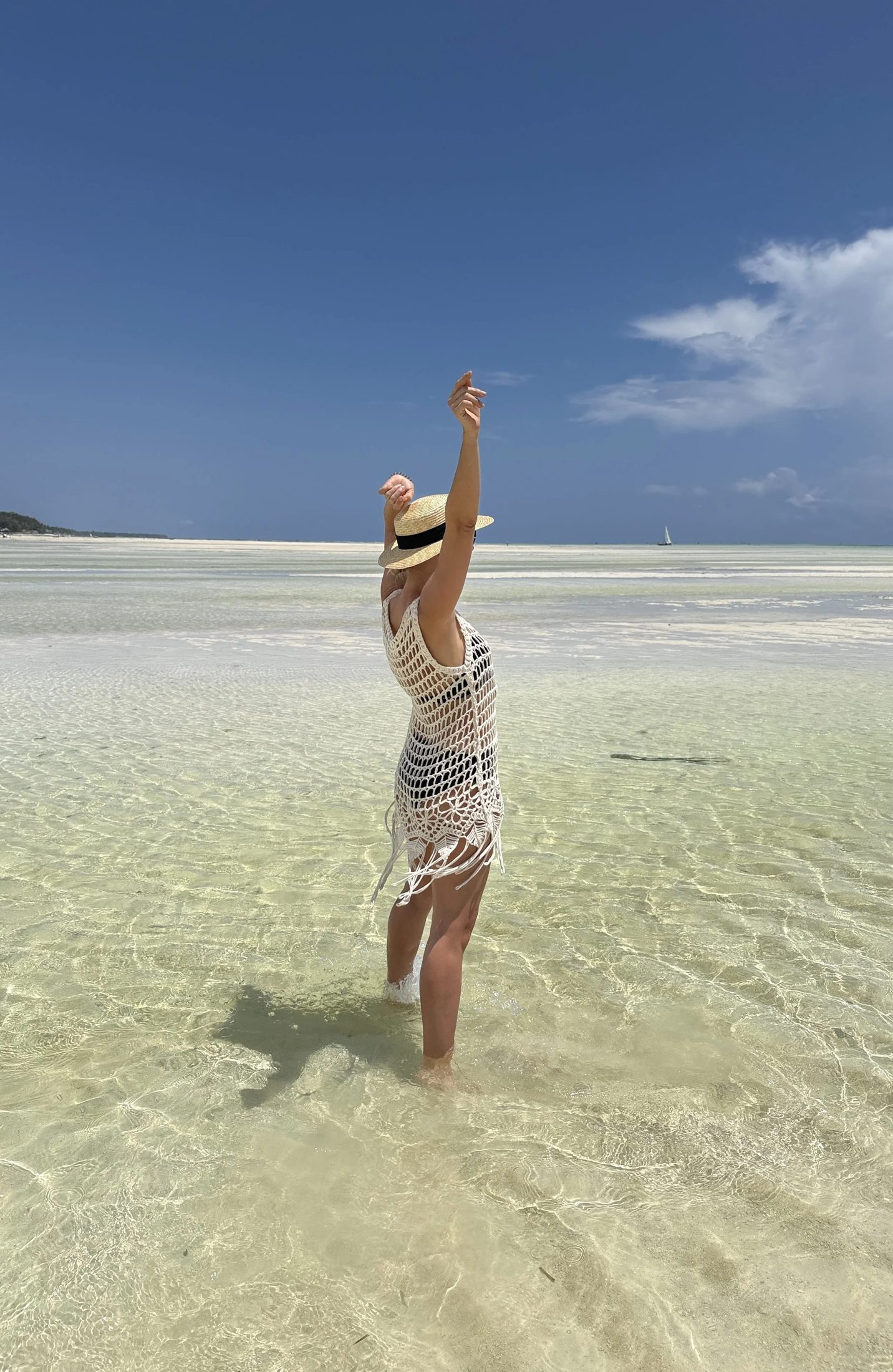 A guest raising her hand to the sky in shallow turquoise water