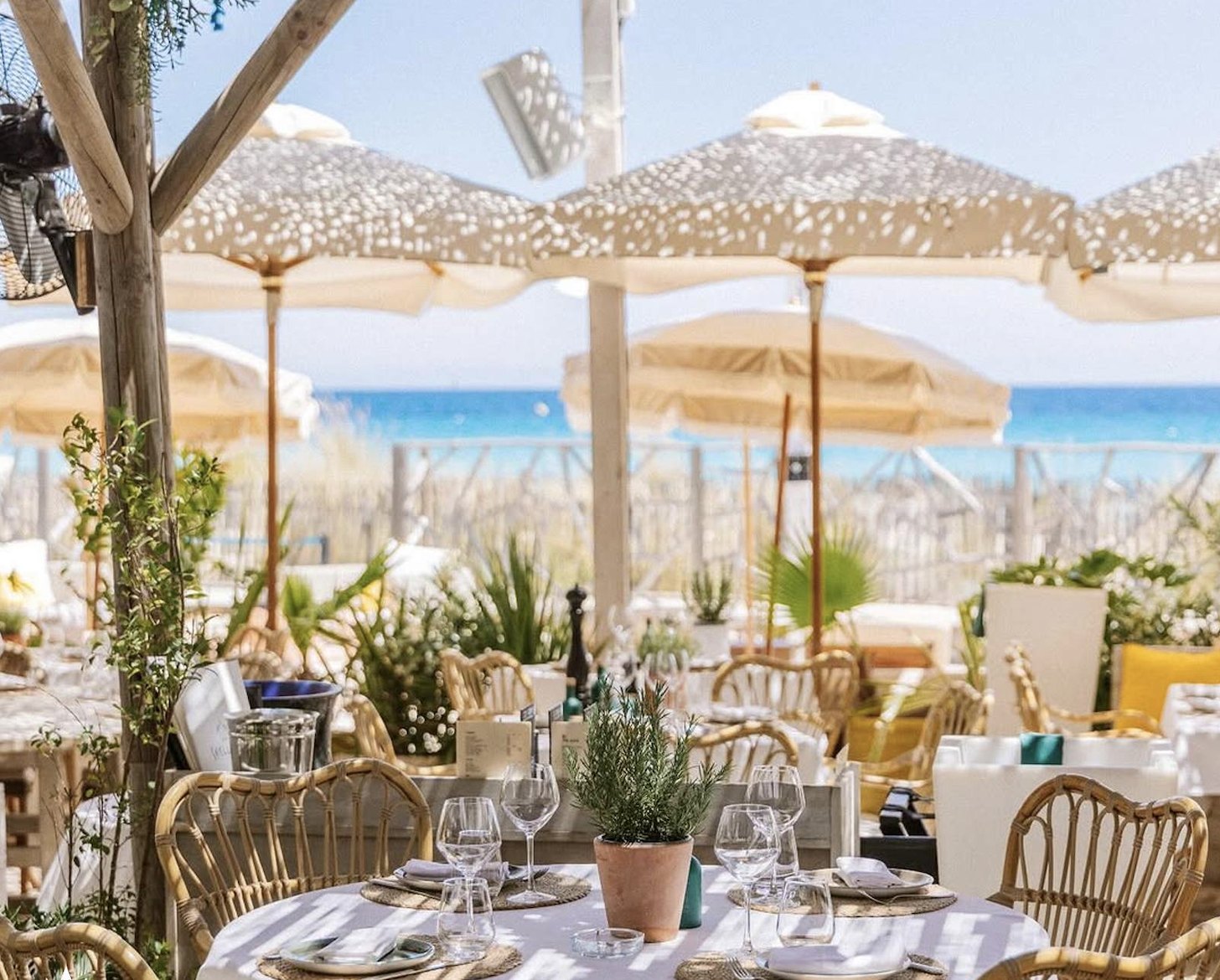 Beach club tables beneath fringed parasols
