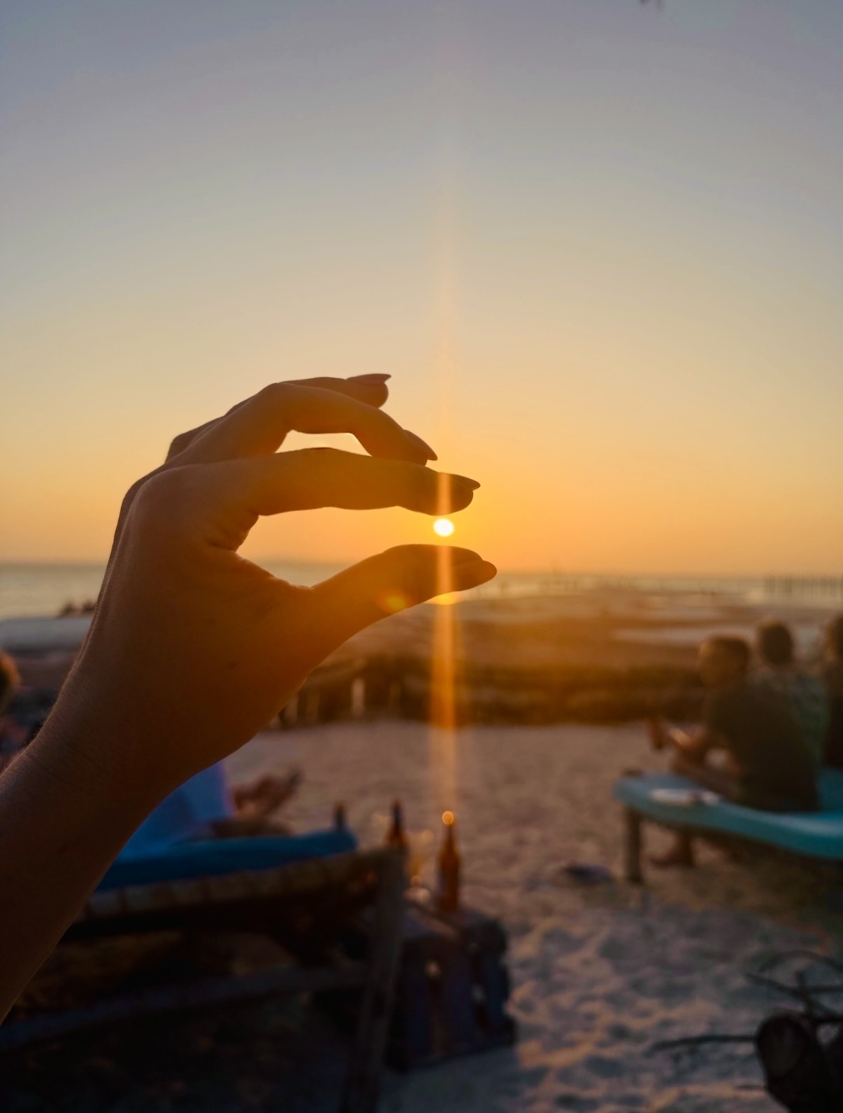 Catching the setting sun between two fingers on the beach